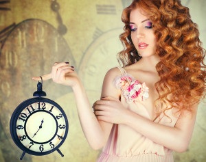 Young beautiful girl holding a large wall clock..against the bac