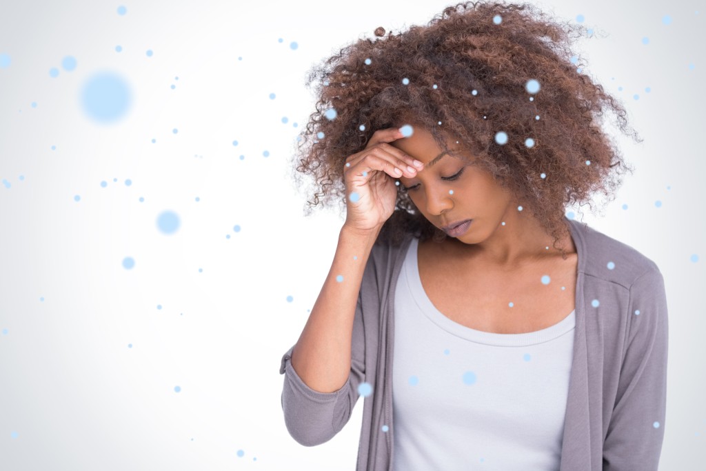 Composite image of sad woman holding her forehead with her hand